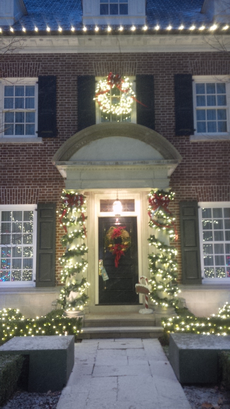 Elegant Lit Garland wrapped pillars with bows at front entrance