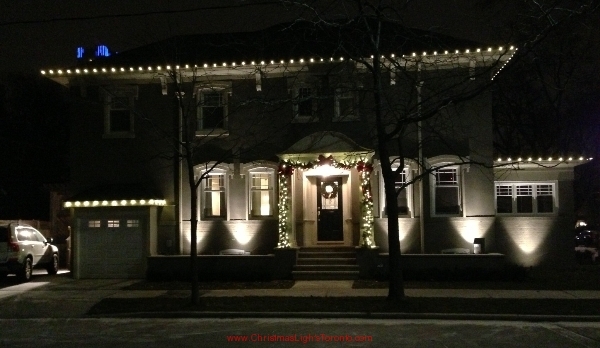 Mid town Toronto home decorated by LawnSavers Professional Christmas Decorators with C9 Led lights and premium garland swag around front entrance